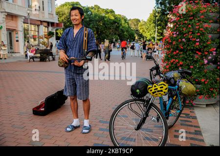 Takashi est un homme de 40 ans d'Okinawa, au Japon. Il y a un an, il était chef de sushi dans sa ville natale. Maintenant, il joue sanshi - instrument traditionnel d'Okinawa dans les rues de Varna, Bulgarie, à plus de 15 000 km de la maison. L'année dernière, après avoir divorcé avec sa femme, Takashi a décidé de prendre le temps de faire ce qu'il voulait toujours faire - voyager dans le monde, rencontrer de nouvelles personnes et partager avec eux des valeurs japonaises traditionnelles - comme chérir notre nature, nos langues et les autres. Il voyage principalement en vélo. Il utilise parfois des trains ou des ferries, mais jamais des avions - ils ne sont pas écologiques mais Banque D'Images