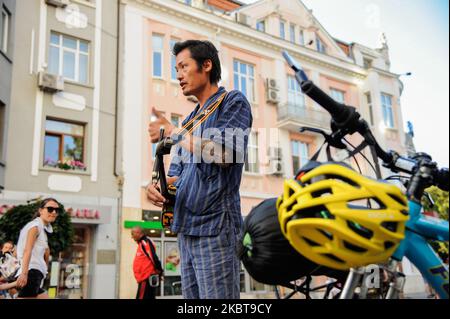 Takashi est un homme de 40 ans d'Okinawa, au Japon. Il y a un an, il était chef de sushi dans sa ville natale. Maintenant, il joue sanshi - instrument traditionnel d'Okinawa dans les rues de Varna, Bulgarie, à plus de 15 000 km de la maison. L'année dernière, après avoir divorcé avec sa femme, Takashi a décidé de prendre le temps de faire ce qu'il voulait toujours faire - voyager dans le monde, rencontrer de nouvelles personnes et partager avec eux des valeurs japonaises traditionnelles - comme chérir notre nature, nos langues et les autres. Il voyage principalement en vélo. Il utilise parfois des trains ou des ferries, mais jamais des avions - ils ne sont pas écologiques mais Banque D'Images