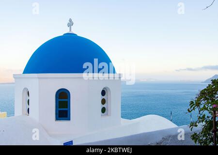 Vue panoramique sur le magnifique paysage pittoresque de la ville d'Oia, Grèce, sur 6 juillet 2020 pendant l'heure magique, le coucher du soleil et les églises à dôme bleu. Maisons ou hôtels avec la célèbre architecture traditionnelle des îles Cyclades au-dessus de la caldeira du volcan et de la mer Égée. L'île de Santorini est l'une des destinations grecques et méditerranéennes les plus célèbres, célèbre pour le volcan actif et le coucher du soleil, elle est considérée comme une destination romantique et relaxante pour les vacances d'été et de lune de miel. Pendant le coucher du soleil, il y a habituellement des milliers de couples, des touristes du monde entier Banque D'Images