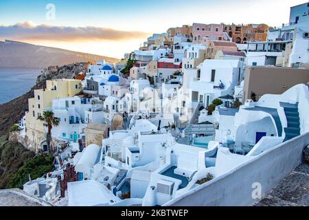 Vue panoramique sur le magnifique paysage pittoresque de la ville d'Oia, Grèce, sur 6 juillet 2020 pendant l'heure magique, le coucher du soleil et les églises à dôme bleu. Maisons ou hôtels avec la célèbre architecture traditionnelle des îles Cyclades au-dessus de la caldeira du volcan et de la mer Égée. L'île de Santorini est l'une des destinations grecques et méditerranéennes les plus célèbres, célèbre pour le volcan actif et le coucher du soleil, elle est considérée comme une destination romantique et relaxante pour les vacances d'été et de lune de miel. Pendant le coucher du soleil, il y a habituellement des milliers de couples, des touristes du monde entier Banque D'Images