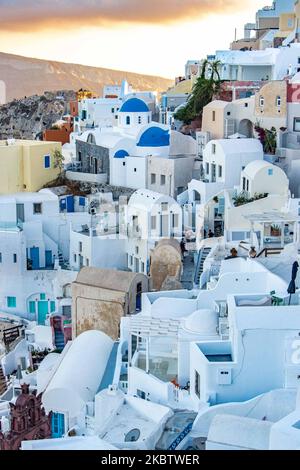 Vue panoramique sur le magnifique paysage pittoresque de la ville d'Oia, Grèce, sur 6 juillet 2020 pendant l'heure magique, le coucher du soleil et les églises à dôme bleu. Maisons ou hôtels avec la célèbre architecture traditionnelle des îles Cyclades au-dessus de la caldeira du volcan et de la mer Égée. L'île de Santorini est l'une des destinations grecques et méditerranéennes les plus célèbres, célèbre pour le volcan actif et le coucher du soleil, elle est considérée comme une destination romantique et relaxante pour les vacances d'été et de lune de miel. Pendant le coucher du soleil, il y a habituellement des milliers de couples, des touristes du monde entier Banque D'Images