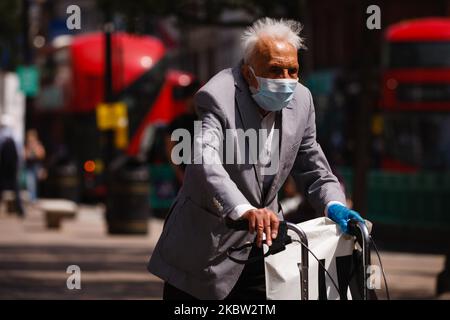 Un homme âgé portant un masque facial et un gant jetable utilise une aide à la marche sur Oxford Street à Londres, en Angleterre, sur 22 juillet 2020. Les données sur les ventes au détail au Royaume-Uni pour le mois de juin, au cours duquel les magasins non essentiels ont été autorisés à rouvrir, seront publiées ce vendredi par l'Office des statistiques nationales (ONS), 24 juillet. Le jour sera également le premier que les gens en Angleterre seront tenus de porter des masques ou d'autres types de couverture de visage dans les magasins et les supermarchés. Depuis la mi-juin, les revêtements faciaux des transports publics sont obligatoires dans toute l'Angleterre. (Photo de David Cliff/NurPhoto) Banque D'Images