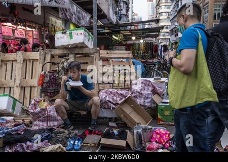 Un homme est vu manger dans la rue comme un homme portant un masque est vu en train de parcourir son produit sur 25 juillet 2020 à Hong Kong, Chine. Hong Kong a signalé aujourd'hui 133 nouveaux cas de Covid-19, ce qui porte le nombre total de cas confirmés à 2 639 et 18 décès à l'intérieur de la ville. Hong Kong a signalé plus de 10 nouveaux cas par jour pendant quatre jours consécutifs, Le gouvernement impose de nouvelles restrictions dans un effort pour courber la propagation de Covid-19, y compris en rendant obligatoire le port d'un masque à l'intérieur et sur le transport public, interdisant la dinde dans les restaurants après 6pm. (Photo de Vernon Yuen/NurPhoto) Banque D'Images