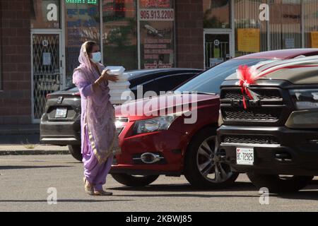 Femme sikh portant un masque facial pour la protéger du nouveau coronavirus (COVID-19) lorsqu'elle livre des boîtes de bonbons indiens à la voiture d'un couple sikh nouvellement marié à Brampton, Ontario, Canada sur 01 août 2020. (Photo de Creative Touch Imaging Ltd./NurPhoto) Banque D'Images