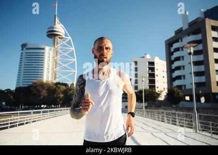 Coureur masculin à Lisbonne. Jeune barbu tatoué gars jogging à l'extérieur, portrait de l'homme actif jogging un jour ensoleillé Banque D'Images