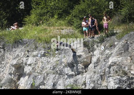 Un homme saute de la falaise au lagon de Zakrzowek à Cracovie, en Pologne, sur 2 août 2020. Zakrzowek, une ancienne carrière de calcaire, située tout près du centre-ville, attire avec un paysage presque méditerranéen - eau turquoise, falaises rocheuses, nature sauvage. Bien qu'il y ait une interdiction stricte de nager dans le lagon, les Cracovie continuent d'utiliser la région et de profiter de sa paix et de sa beauté les jours chauds. (Photo de Beata Zawrzel/NurPhoto) Banque D'Images