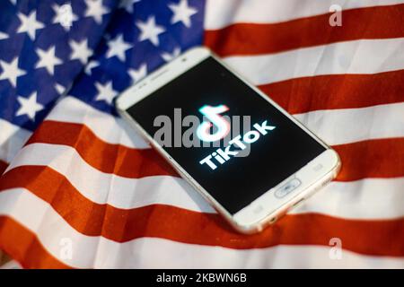 Le logo TikTok Closeup est affiché sur l'écran d'un téléphone, d'un smartphone sur le drapeau américain ou américain, le drapeau national des États-Unis, dans cette illustration à exposition multiple. Tik Tok est un service chinois de réseautage social de partage de vidéos appartenant à une société de technologie Internet basée à Pékin, ByteDance. Il est utilisé pour créer de courtes vidéos de danse, de synchronisation des lèvres, de comédie et de talent. ByteDance a lancé l'application TikTok pour iOS et Android en 2017 et plus tôt en septembre 2016 Douyin fror le marché en Chine. TikTok est devenu l'application la plus téléchargée aux États-Unis en octobre 2018. Président des États-Unis Donald Trump i Banque D'Images