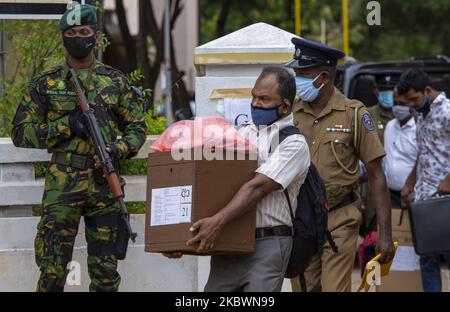 Un responsable des élections sri-lankais portant un masque de protection porte une urne sous la sécurité fournie par les policiers portant des masques de protection à transporter au bureau de vote respectif dans un centre de répartition du matériel électoral à Anuradhapura, au Sri Lanka, sur 4 août 2020. Sri Lanka tiendra des élections législatives le 05 août 2020. (Photo de Thharaka Basnayaka/NurPhoto) Banque D'Images