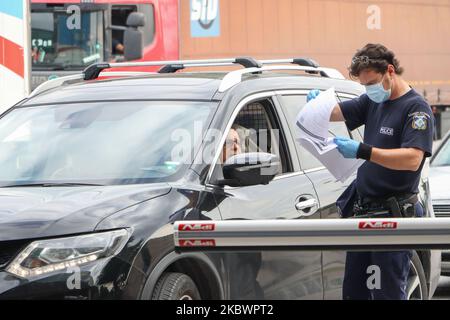 Un agent de police vérifie les documents requis pour que la voiture entre en Grèce. La Grèce vérifie les touristes arrivant aux frontières gréco-bulgares de 31 juillet 2020 pour Covid-19. Les voyageurs en voiture et en bus de toute l'Europe mais surtout de Bulgarie, Roumanie, République tchèque et Pologne arrivent aux frontières grecques bulgares de Promahona - Kulata, point d'entrée en Grèce pour les vacances et ils sont contrôlés pour les coronavirus. La Grèce a levé l'interdiction de voyager depuis 1 juillet et a relancé la saison touristique. Les touristes arrivant doivent porter le formulaire spécial de recherche de passager pour chaque individu, un nouveau RE Banque D'Images