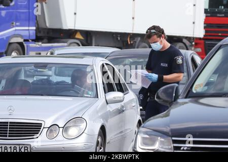 Un agent de police vérifie les documents requis pour que la voiture entre en Grèce. La Grèce vérifie les touristes arrivant aux frontières gréco-bulgares de 31 juillet 2020 pour Covid-19. Les voyageurs en voiture et en bus de toute l'Europe mais surtout de Bulgarie, Roumanie, République tchèque et Pologne arrivent aux frontières grecques bulgares de Promahona - Kulata, point d'entrée en Grèce pour les vacances et ils sont contrôlés pour les coronavirus. La Grèce a levé l'interdiction de voyager depuis 1 juillet et a relancé la saison touristique. Les touristes arrivant doivent porter le formulaire spécial de recherche de passager pour chaque individu, un nouveau RE Banque D'Images