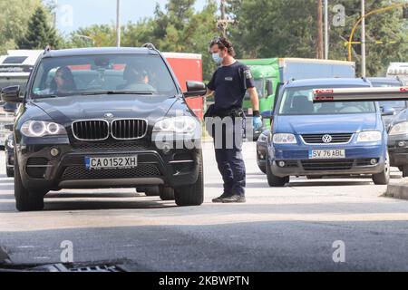 Un agent de police vérifie les documents requis pour que la voiture entre en Grèce. La Grèce vérifie les touristes arrivant aux frontières gréco-bulgares de 31 juillet 2020 pour Covid-19. Les voyageurs en voiture et en bus de toute l'Europe mais surtout de Bulgarie, Roumanie, République tchèque et Pologne arrivent aux frontières grecques bulgares de Promahona - Kulata, point d'entrée en Grèce pour les vacances et ils sont contrôlés pour les coronavirus. La Grèce a levé l'interdiction de voyager depuis 1 juillet et a relancé la saison touristique. Les touristes arrivant doivent porter le formulaire spécial de recherche de passager pour chaque individu, un nouveau RE Banque D'Images