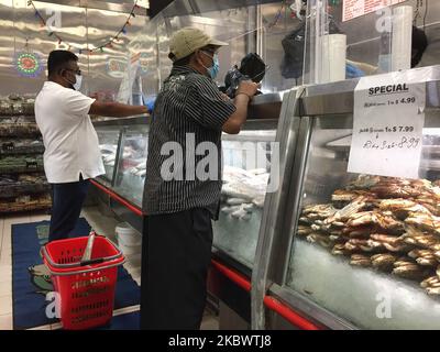 Les clients portant un masque facial pour les protéger du nouveau coronavirus (COVID-19) en attendant d'acheter du poisson sur un marché sri-lankais des produits de la mer à Toronto, Ontario, Canada on 06 août 2020. Les courses d'épicerie sont devenues une expérience traumatisante pour de nombreux Canadiens qui s'inquiètent de contracter le virus. (Photo de Creative Touch Imaging Ltd./NurPhoto) Banque D'Images