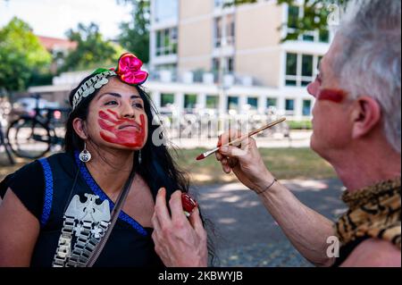 Un homme peint une main rouge sur le visage d'une femme autochtone avant que la manifestation pour la défense des droits des peuples autochtones dans le monde entier ait eu lieu à Amsterdam, pays-Bas, sur 9 août 2020. (Photo par Romy Arroyo Fernandez/NurPhoto) Banque D'Images