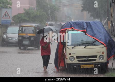 Les navetteurs et les piétons sont vus sur la route pendant qu'ils se déplacent, ils jettent la pluie et les eaux de connexion comme il pleut dans l'est de l'état indien Odisha capitale, Bhubaneswar, sur 10 août 2020. (Photo par STR/NurPhoto) Banque D'Images