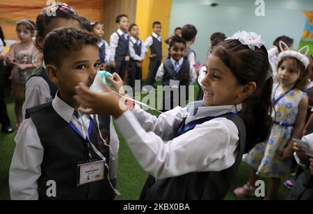 Une fille applique un masque sur le visage d'un autre garçon lors d'une séance de sensibilisation sur la coronavirus COVID-19 tenue par un jardin d'enfants local à Gaza, sur 10 août 2020, Alors que les installations éducatives de l'enclave palestinienne ont rouvert pour la nouvelle année universitaire 2020-2021, suite à un assouplissement des restrictions en cas de pandémie. (Photo de Majdi Fathi/NurPhoto) Banque D'Images