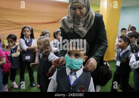 Un enseignant applique un masque sur le visage d'un autre garçon lors d'une séance de sensibilisation sur la coronavirus COVID-19 tenue par un jardin d'enfants local à Gaza, sur 10 août 2020, Alors que les installations éducatives de l'enclave palestinienne ont rouvert pour la nouvelle année universitaire 2020-2021, suite à un assouplissement des restrictions en cas de pandémie. (Photo de Majdi Fathi/NurPhoto) Banque D'Images