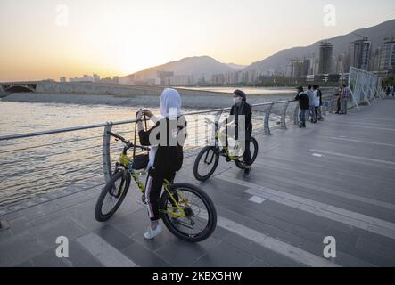 Deux femmes iraniennes portant un masque facial protecteur reposent sur leurs bicyclettes dans le complexe récréatif de lac artificiel Chitgar, dans le nord-ouest de Téhéran, à la suite de l'épidémie de COVID-19 en Iran, au 13 août 2020. Les gens qui vivent à Téhéran semblent s'habituer au nouveau coronavirus et utiliser le masque comme une routine quotidienne. (Photo de Morteza Nikoubazl/NurPhoto) Banque D'Images