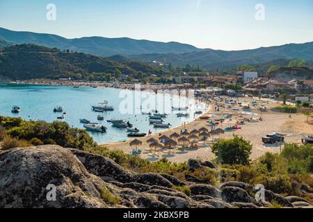 Vue panoramique sur la plage de Kalamitsi. Foule de touristes à la célèbre et populaire plage de Kalamitsi située à la pointe sud de la péninsule de Sithonia à Chalkidiki dans le nord de la Grèce. Les gens s'amusent à la plage en Grèce car ils se détendent à l'ombre des parasols, plongée en apnée, plongée sous-marine, natation dans les eaux cristallines tropicales exotiques, sports nautiques, location de bateaux, prendre un verre dans les bars de la plage ou prendre un bain de soleil sur le sable doré et profiter de la vie sur la plage sous le ciel bleu ensoleillé. Il y a une petite île également située près de la rive. Le gouvernement local est addi Banque D'Images