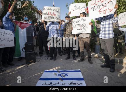 Les manifestants iraniens détiennent un drapeau palestinien et des pancartes tandis qu'un drapeau israélien est vu sur le terrain lors d'une manifestation devant l'ambassade des Émirats arabes Unis dans le nord-ouest de Téhéran, en 15 août 2020. Un groupe d’étudiants iraniens de l’Université de Téhéran se réunit devant l’ambassade des Émirats arabes Unis pour manifester contre les relations diplomatiques entre les Émirats arabes Unis et Israël. (Photo de Morteza Nikoubazl/NurPhoto) Banque D'Images