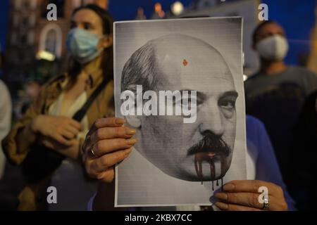 Un manifestant tient une image d'Alexandre Loukachenko. Samedi soir, des membres de la diaspora biélorusse locale, des militants et des supporters locaux se tapis pour exprimer leur solidarité avec les Biélorusses lors du rassemblement de solidarité organisé sur la place du marché principal de Cracovie. Sur 15 août 2020, à Cracovie, en Pologne. (Photo par Artur Widak/NurPhoto) Banque D'Images