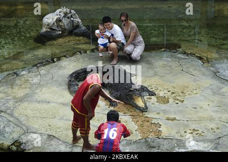 Les thaïlandais posant avec un gros crocodile à la fin d'un spectacle à la ferme et au zoo de crocodiles de Samutprakarn, province de Samut Prakan, Thaïlande, le 22 août 2020. La ferme et le zoo prétendent être la plus grande ferme de crocodiles au monde avec plus de 40 000 crocodiles d'eau douce et marins, et offre des spectacles tels que la lutte de crocodiles pour attirer les touristes, de retour ouvert au milieu de l'épidémie du coronavirus. (Photo par Anusak Laowilas/NurPhoto) Banque D'Images