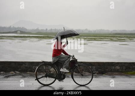 Un cachemiri passe son vélo sur les rives du lac Dal alors que les précipitations se poursuivent dans la vallée de Srinagar, au Cachemire administré par l'Inde, le 27 août 2020. (Photo de Muzamil Mattoo/NurPhoto) Banque D'Images