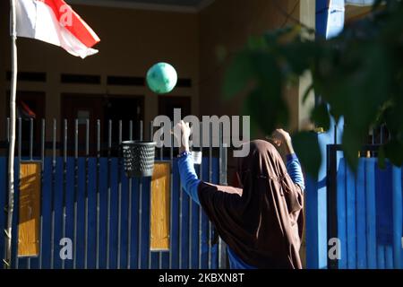 LIA (11), une étudiante de 6 e année à l'école primaire, tente de jeter la balle en plastique à la corbeille utilisée comme panier de basket-ball de fortune, comme elle fait sa tâche d'entraînement sportif de son professeur devant sa maison dans le village de Wanasari, Bekasi regency, province de Java Ouest, sur 28 août 2020. Le gouvernement indonésien ferme encore les écoles et met en place un système d'apprentissage en ligne pour prévenir la transmission du coronavirus Covid-19, le nombre de nouveaux cas continuant d'augmenter. (Photo par Aditya Irawan/NurPhoto) Banque D'Images