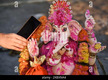 Un dévot murmure un souhait par téléphone à l'oreille d'une idole de la déité hindoue Ganesha, dans le cadre d'un rituel à l'occasion de Ganesha Chaturthi, avant immersion dans le fleuve Brahmaputra, pendant les célébrations de Ganesh Chaturthi, à Guwahati, Assam, Inde vendredi, 28 août, 2020. (Photo de David Talukdar/NurPhoto) Banque D'Images