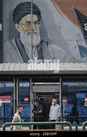 Deux hommes iraniens portant un masque facial protecteur se tiennent dans un arrêt de bus sous les portraits du Guide suprême de l'Iran, l'ayatollah Ali Khamenei, dans le quartier des affaires de Téhéran, au milieu du nouveau coronavirus (COVID-19) qui a éclaté en Iran, sur 5 juillet 2020. (Photo de Morteza Nikoubazl/NurPhoto) Banque D'Images