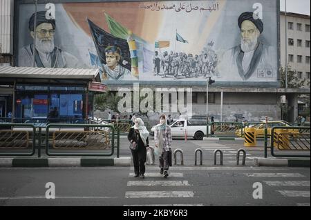 Deux femmes iraniennes portant un masque facial protecteur traversent une avenue en se promenant sous des portraits du Guide suprême de l'Iran, l'ayatollah Ali Khamenei (L) et de feu le dirigeant, l'ayatollah Ruhollah Khomeini, dans le quartier des affaires de Téhéran, au milieu du nouveau coronavirus (COVID-19) qui a éclaté en Iran, sur 5 juillet 2020. (Photo de Morteza Nikoubazl/NurPhoto) Banque D'Images