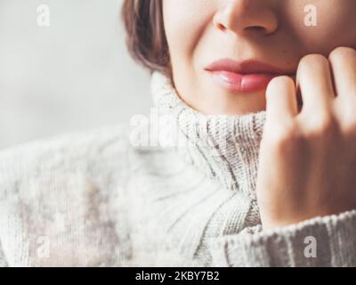 Gros plan d'une femme qui se blottir dans un chandail gris chaud.Tenue décontractée par temps froid en hiver. Banque D'Images