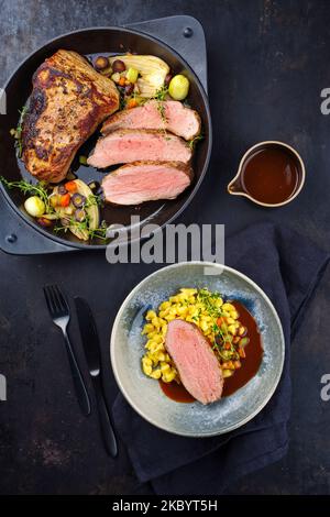 Tranches de veau torréfié Tafelspitz avec spaetzle souabe servies avec une sauce à la bière foncée comme vue de dessus dans un bol et un pot design Banque D'Images