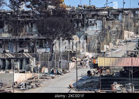 Les séquelles de l'incendie dans le camp de réfugiés de Moria et les oliveraies voisines. Les migrants et les réfugiés sont à la recherche de leurs effets personnels ou d'articles utiles pour leur nouvelle résidence à Kara Tepe, à l'intérieur de la zone brûlée des tentes, des installations officielles et des cendres, pour les y déplacer. Les demandeurs d'asile ont été transférés dans le nouveau camp de réfugiés de Kara Tepe - Mavrovouni ancienne zone militaire, champ de tir de l'armée hellénique, près de la ville de Mytilène, sur l'île de Lesbos, en Grèce. Le nouveau camp temporaire a été créé après le feu de 9 septembre 2020, l'un des plus grands réfugiés d'Europe Banque D'Images