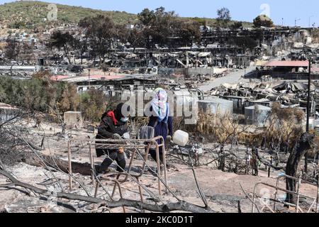 Les séquelles de l'incendie dans le camp de réfugiés de Moria et les oliveraies voisines. Les migrants et les réfugiés sont à la recherche de leurs effets personnels ou d'articles utiles pour leur nouvelle résidence à Kara Tepe, à l'intérieur de la zone brûlée des tentes, des installations officielles et des cendres, pour les y déplacer. Les demandeurs d'asile ont été transférés dans le nouveau camp de réfugiés de Kara Tepe - Mavrovouni ancienne zone militaire, champ de tir de l'armée hellénique, près de la ville de Mytilène, sur l'île de Lesbos, en Grèce. Le nouveau camp temporaire a été créé après le feu de 9 septembre 2020, l'un des plus grands réfugiés d'Europe Banque D'Images