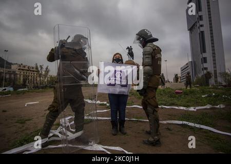 Une femme adulte plus âgée porte un drapeau avec un symbole faisant référence à l'« Apruebo » (j'approuve une nouvelle constitution politique, quelques jours après le plébiscite). Elle est intimidée et harcelée par la police anti-émeute de Carabineros de Chili pour se retirer de l'espace public. Au milieu de la manifestation et de la protestation des infirmières à être reconnu comme un professionnel dans le code de la santé. Sur 25 septembre 2020, à Santiago du Chili. (Photo de Claudio Abarca Sandoval/NurPhoto) Banque D'Images