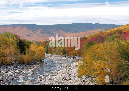 Vue panoramique sur les montagnes lointaines de la forêt nationale de White Mountain avec feuillage d'automne vibrant le long des rives de la rivière Pegewegasset rocheuse dans le New Hampshire. Banque D'Images