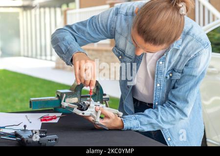 Jeune homme méconnaissable fixant un petit drone à la main avec un tournevis comme homme de main dans le jardin Banque D'Images