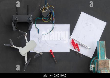 Vue en hauteur d'un petit quadriptère et d'une télécommande avec une variété d'outils sur une table de réparation noire Banque D'Images