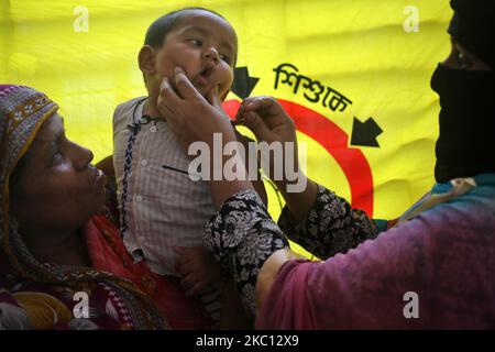 Un agent de santé (R) administre des gouttes de vaccin contre la polio à un enfant lors d'une campagne de vaccination contre la polio à Magura, au Bangladesh, dimanche, au 04 octobre 2020. (Photo de Syed Mahamudur Rahman/NurPhoto) Banque D'Images