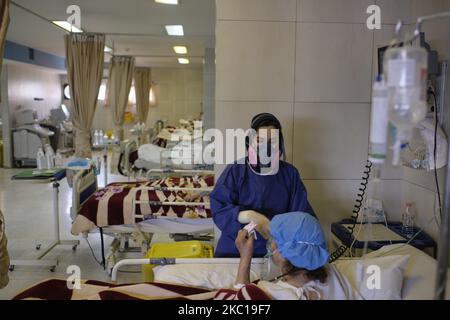 Un personnel médical iranien portant une combinaison protectrice prend soin d'une femme âgée qui a été infectée par le nouveau coronavirus dans une section COVID-19 d'un hôpital du sud de Téhéran, sur 6 octobre 2020. Les autorités sanitaires iraniennes avertissent que Téhéran a franchi la ligne rouge et que le personnel médical des hôpitaux sera confronté à des problèmes et ne sera pas en mesure de contrôler l'épidémie de la nouvelle coronavirus (COVID-19) dans le pays, si les gens ne suivent pas les protocoles de santé. (Photo de Morteza Nikoubazl/NurPhoto) Banque D'Images