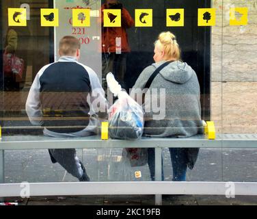 Passagers en surpoids à un arrêt de bus sous les symboles emblématiques de Glasgow de son mythe Banque D'Images