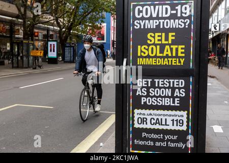 Un homme dans un masque facial protecteur est vu à cheval sur un panneau d'affichage Covid-19 alors que les cas de Covid-19 augmentent pendant la deuxième vague de coronavirus à Londres, Angleterre sur 11 octobre 2020. Le panneau d'affichage appelle le public à s'auto-isoler en cas de syndromes Covid-19. (Photo par Dominika Zarzycka/NurPhoto) Banque D'Images