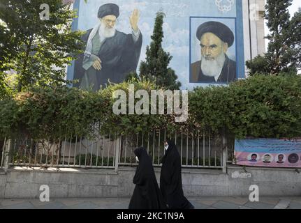 Deux femmes iraniennes voilées portant un masque facial protecteur se promontent sous les portraits de l’ayatollah Ali Khamenei (L), le Guide suprême iranien, et de l’ayatollah Ruhollah Khomeini, l’ancien dirigeant du pays, dans le nord de Téhéran, sur 12 octobre 2020. Les personnes vivant à Téhéran doivent porter un masque facial protecteur si elles veulent apparaître dans les lieux publics comme la nouvelle maladie à coronavirus (COVID-19) qui augmente rapidement dans la capitale, selon une ordonnance des gouvernements iraniens et des responsables de la santé. (Photo de Morteza Nikoubazl/NurPhoto) Banque D'Images