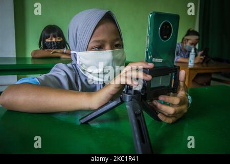 Les élèves utilisent des smartphones pour travailler sur des devoirs scolaires en ligne à l'aide d'un réseau Internet gratuit tout en pratiquant la distanciation physique au sous-district de Rumah Pintar à Semarang, province de Java central, Indonésie sur 11 octobre 2020. Le Rumah Pintar est situé à la mosquée Al Ikhlas et est géré par des résidents et soutenu par PT Pertamina. Bien que le gouvernement indonésien impose une nouvelle ère normale, les autorités locales ferment encore les écoles dans la zone à haut risque de la propagation de Covid-19 et exhorte les élèves à effectuer des études à domicile en utilisant l'apprentissage en ligne de leurs enseignants. (Photo de WF Sihardian/NurPhoto) Banque D'Images