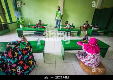 Les élèves utilisent des smartphones pour travailler sur des devoirs scolaires en ligne à l'aide d'un réseau Internet gratuit tout en pratiquant la distanciation physique au sous-district de Rumah Pintar à Semarang, province de Java central, Indonésie sur 11 octobre 2020. Le Rumah Pintar est situé à la mosquée Al Ikhlas et est géré par des résidents et soutenu par PT Pertamina. Bien que le gouvernement indonésien impose une nouvelle ère normale, les autorités locales ferment encore les écoles dans la zone à haut risque de la propagation de Covid-19 et exhorte les élèves à effectuer des études à domicile en utilisant l'apprentissage en ligne de leurs enseignants. (Photo de WF Sihardian/NurPhoto) Banque D'Images