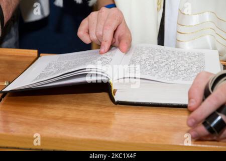 Un jeune homme qui pointe sur une phrase dans un livre de la bible (sefer torah), tout en lisant une prière à un rituel juif (cérémonie du Bar Mitzvah) Banque D'Images