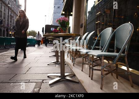 Une femme passe devant des tables extérieures vides dans un restaurant de Piccadilly à Londres, en Angleterre, sur 15 octobre 2020. Londres sera placée sous le coup de mesures de confinement du coronavirus de niveau 2 à partir de ce week-end, ce qui va introduire une interdiction pour les personnes de différents ménages de se mélanger n'importe où à l'intérieur, ce qui est une préoccupation particulière pour le secteur déjà gravement touché de l'hôtellerie. Plusieurs autres régions du pays doivent également voir leurs restrictions Covid-19 renforcées de la même manière. Le système à trois niveaux pour l'Angleterre est entré en vigueur cette semaine, chaque région du pays étant classée comme étant sur un niveau moyen, élevé Banque D'Images