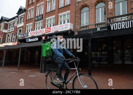 Un jeune homme sur un vélo passant devant des cafés et des bars fermés. Confinement partiel et vie quotidienne dans la ville d'Eindhoven, aux pays-Bas, avec des personnes portant un masque facial lorsqu'elles sont à l'extérieur ou sur la bicyclette comme mesure de protection contre la propagation de l'épidémie de coronavirus Covid-19. Le mardi 13 octobre 2020, le Premier ministre néerlandais Mark Rutte a annoncé que les pays-Bas doivent revenir à un verrouillage partiel, fermer les bars, les cafés et les restaurants, l'utilisation obligatoire du masque facial à l'intérieur, la limitation au nombre de personnes se rassemblent à l'intérieur, les activités sportives et plus sont également affectés Banque D'Images