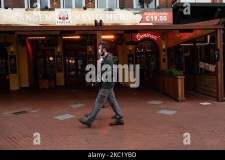 Les gens d'Eindhoven passent devant des cafés et des bars fermés pendant le confinement partiel et la vie quotidienne dans la ville d'Eindhoven aux pays-Bas avec des gens portant un masque facial lorsqu'ils sont à l'extérieur ou à vélo comme mesure de protection contre la propagation de l'épidémie de coronavirus Covid-19. Le mardi 13 octobre 2020, le Premier ministre néerlandais Mark Rutte a annoncé que les pays-Bas doivent revenir à un verrouillage partiel, la fermeture des bars, cafés et restaurants, l'utilisation obligatoire du masque facial à l'intérieur, la limitation au nombre de personnes se rassemblent à l'intérieur, les activités sportives et plus sont également un Banque D'Images