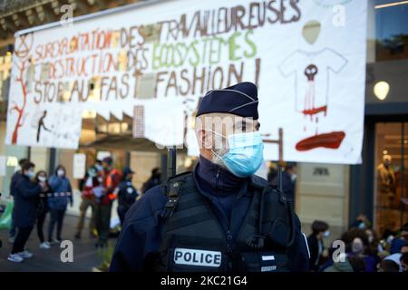 Un policier veille sur les activistes enchaînés aux portes du magasin Zara. Des membres et des activistes de l'ONG XR (rébellion d'extinction) et des jeunes pour le climat ont organisé une journée nationale de protestation contre la mode rapide. Ils ont bloqué les portes d'entrée d'un magasin Zara se faisant enchaîner devant le magasin et ont été délogés par la police après deux heures. Ils veulent sensibiliser à l'empreinte carbone et à l'empreinte écologique de la mode rapide. Des actions similaires ont eu lieu ailleurs en France. Sur 17 octobre 2020 à Toulouse (photo d'Alain Pitton/NurPhoto) Banque D'Images